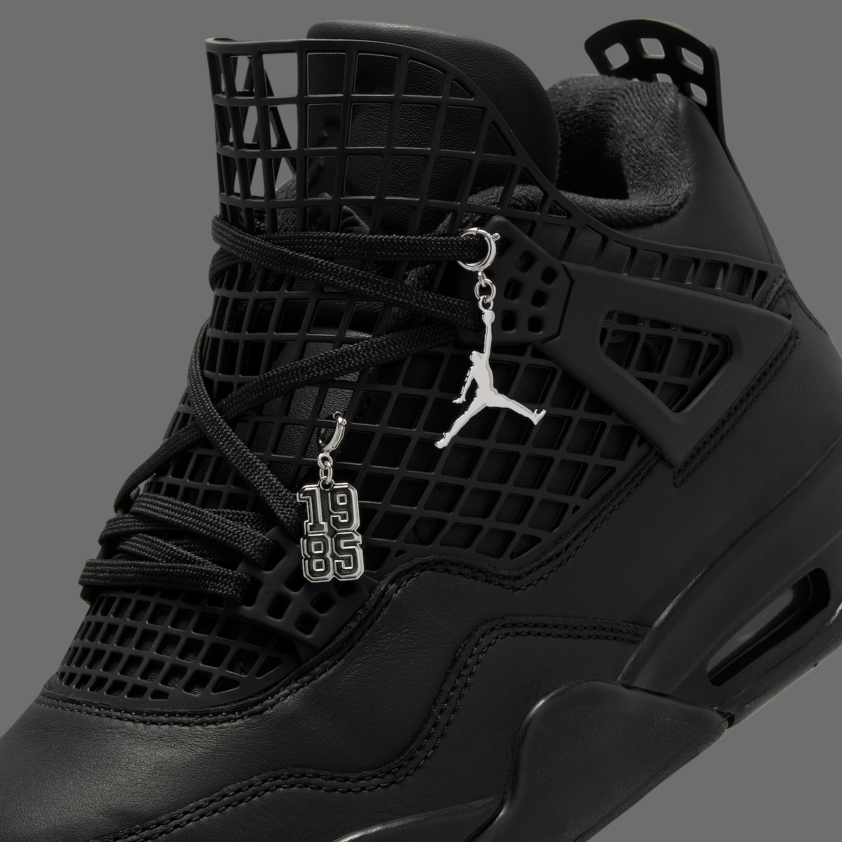 Detailed shot of the Air Jordan 4 NET Black laces with silver Jumpman logo charm and '1985' tag on the laces.