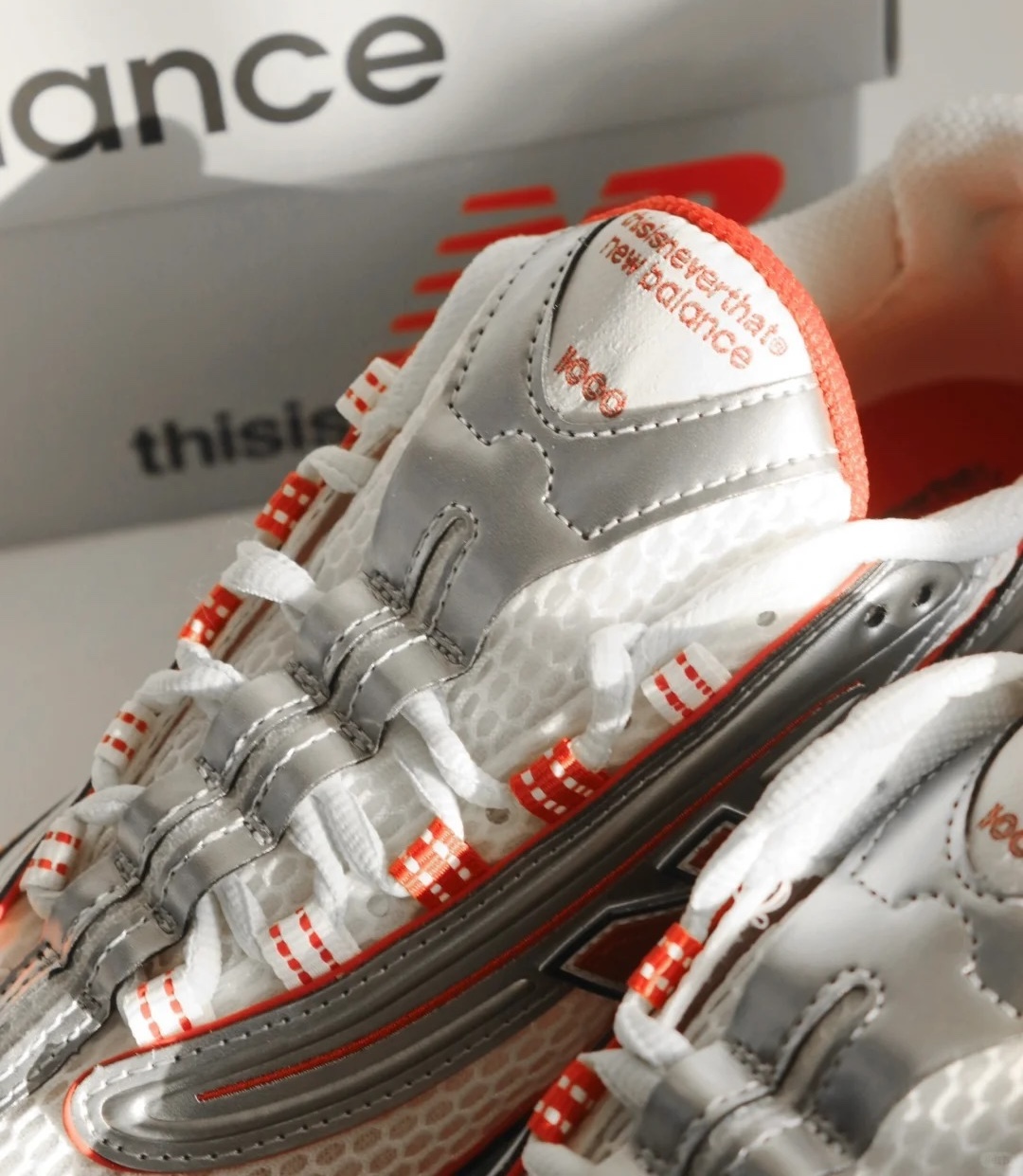Close-up of thisisneverthat x New Balance 1000 M1000TI highlighting the metallic silver tongue, red-accented laces, and dual-branded detailing near the lace eyelets.