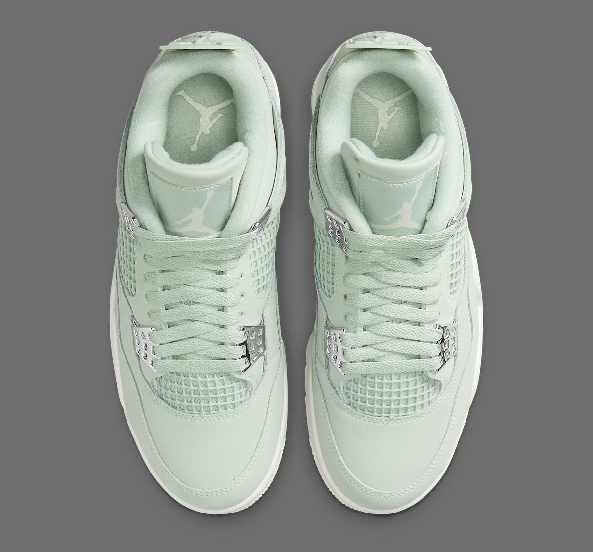 Overhead view of the Air Jordan 4 'Seafoam' showing the symmetrical lacing system, mesh netting on the tongue, and the tonal Jumpman logo printed on the padded tongue and insoles, all in a soft green hue.