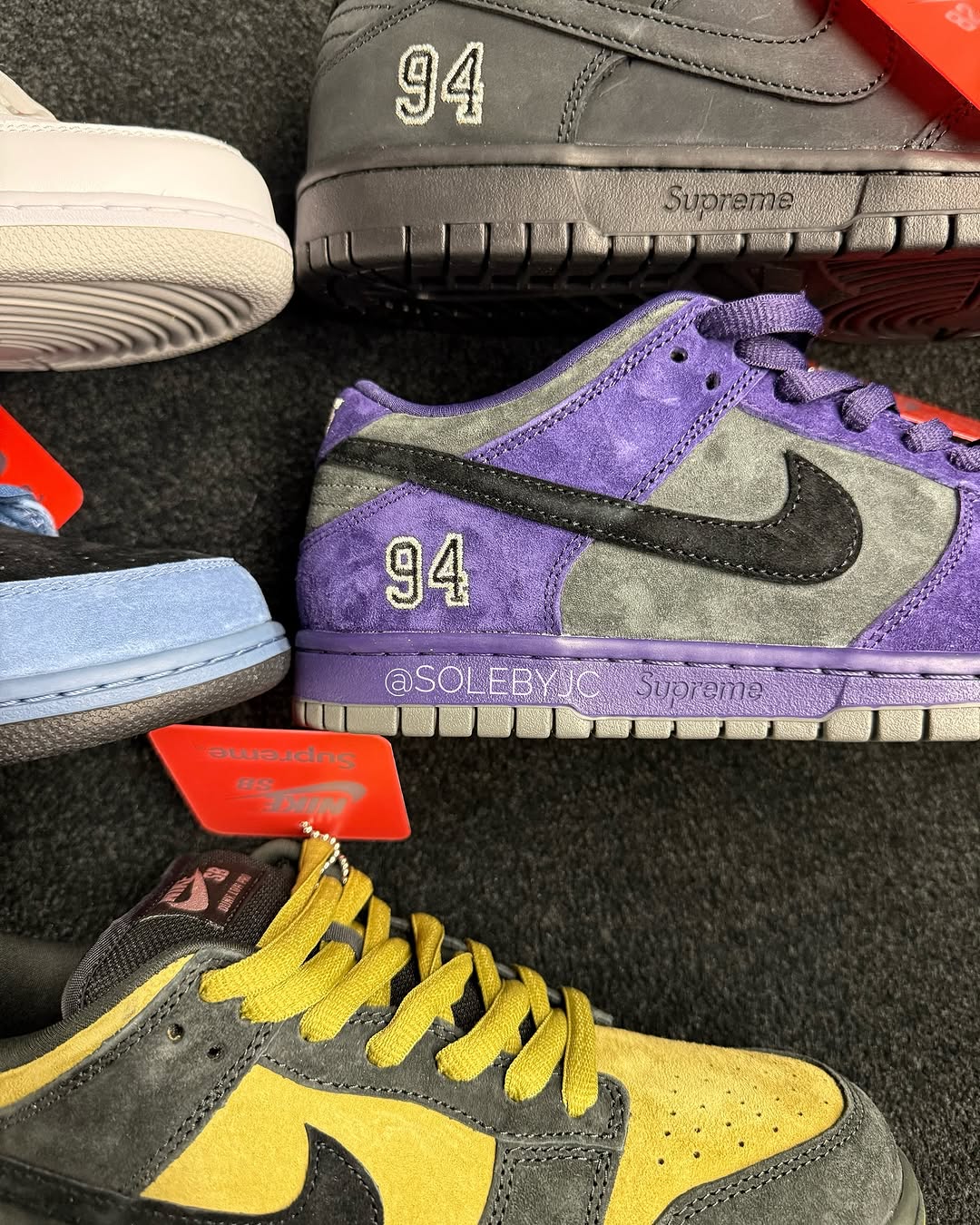 Detailed view of Supreme x Nike SB Dunk Low 2025 in Purple/Grey and Yellow/Black colorways. The sneakers feature suede construction, Supreme branding, and contrast stitching.