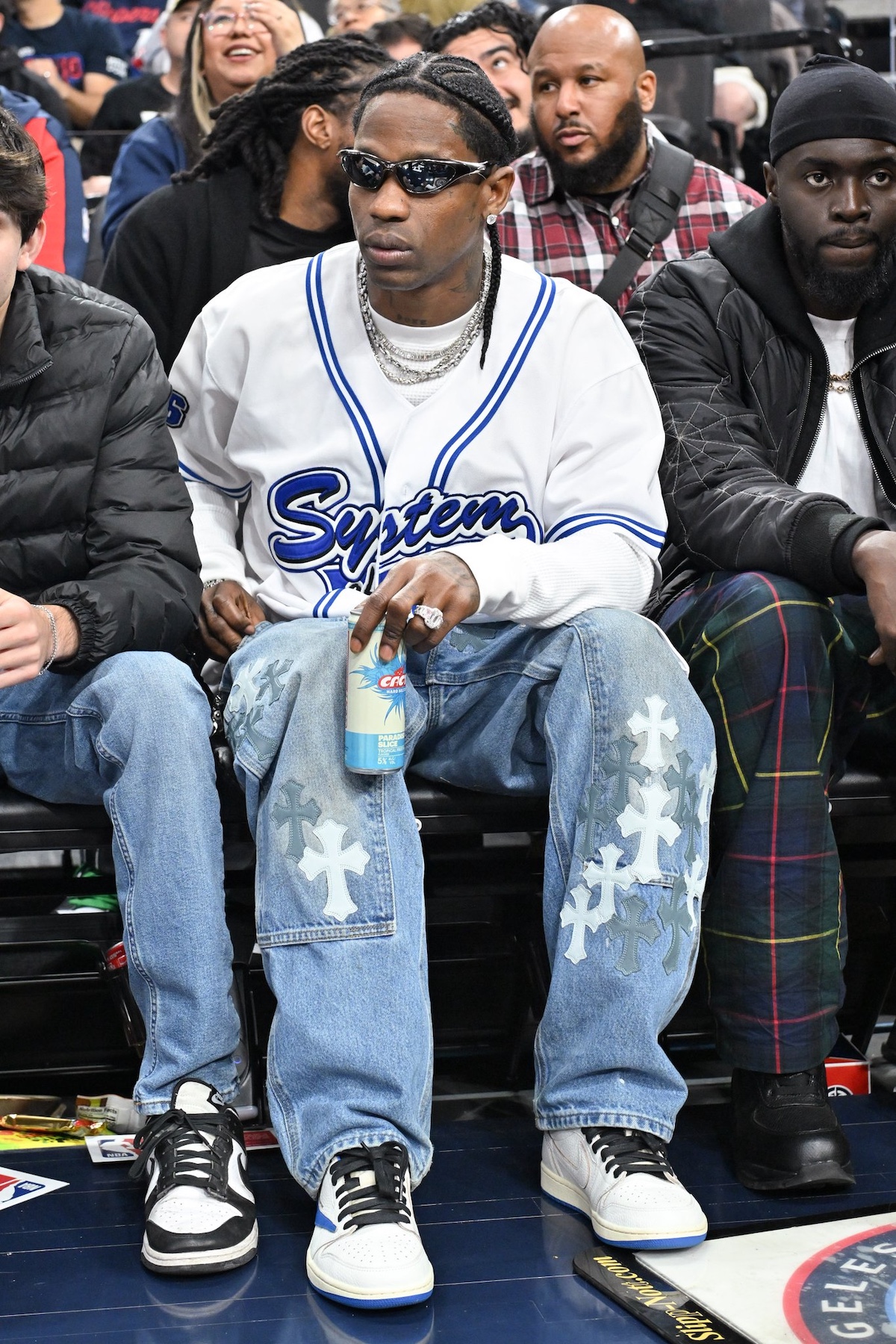 Travis Scott wearing his upcoming Air Jordan 1 Low in collaboration with Fragment, while courtside in System jersey and Chrome Hearts jeans.