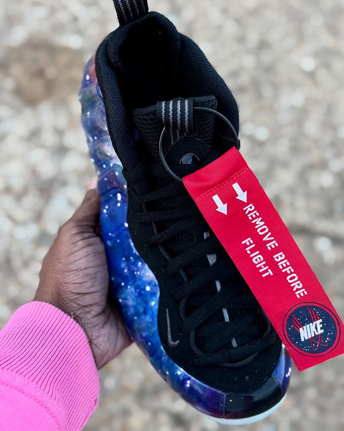 Nike Air Foamposite One Galaxy 2025 top-down view highlighting the black mesh tongue, red Remove Before Flight tag, and looped pull tabs for easy wear