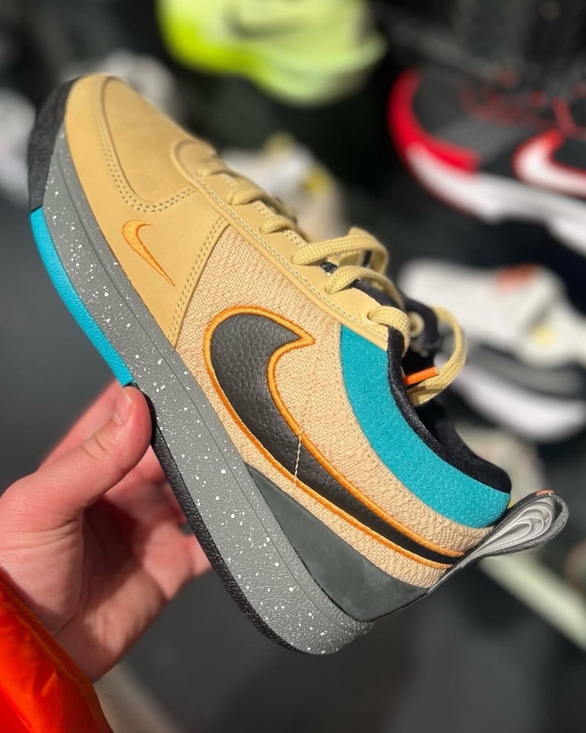 Nike Book 1 Mowabb IF2406-200 side view showcasing its tan suede upper with black leather Swoosh, orange accents, and blue detailing on the heel
