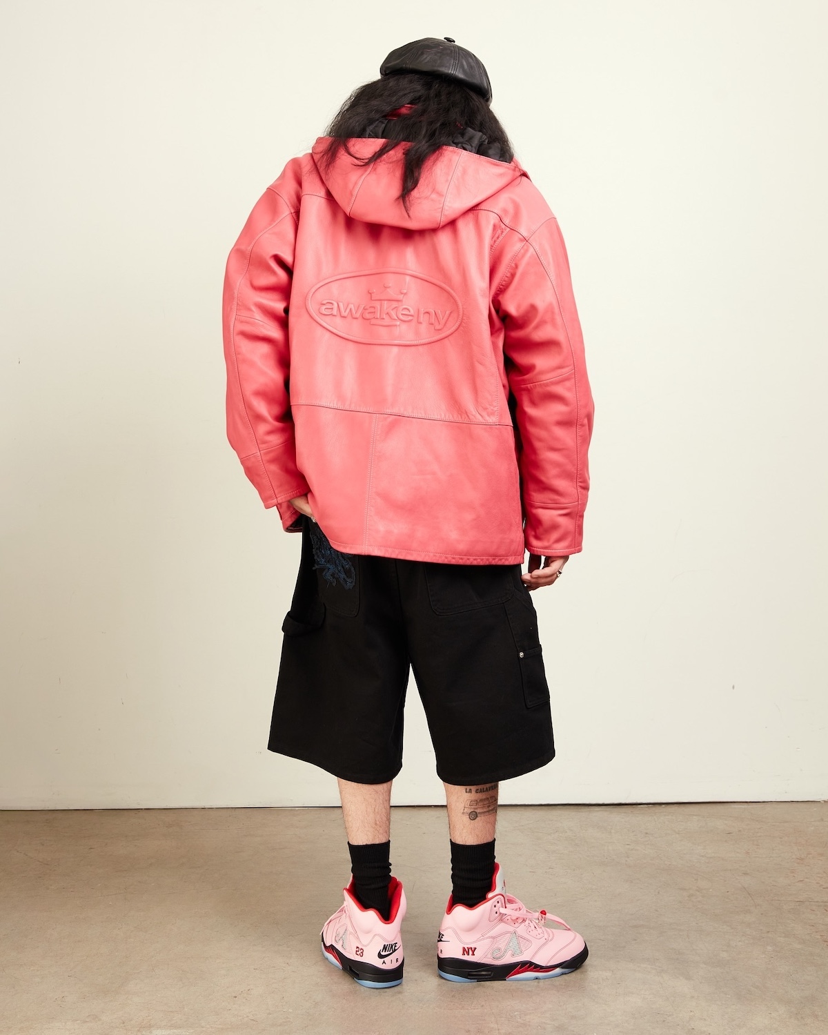 Awake NY x Air Jordan 5 Arctic Pink 2025 on-foot look paired with a bold red Awake NY jacket and black cargo shorts, showcasing signature branding and vibrant color blocking.