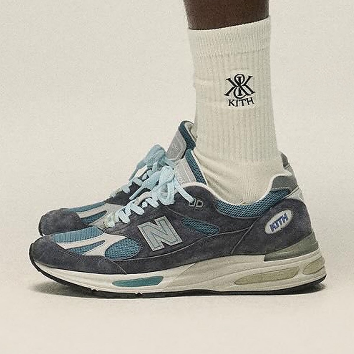 Side view of the Kith x New Balance 991v2 for Spring 2025 featuring icy blue laces and vintage midsole