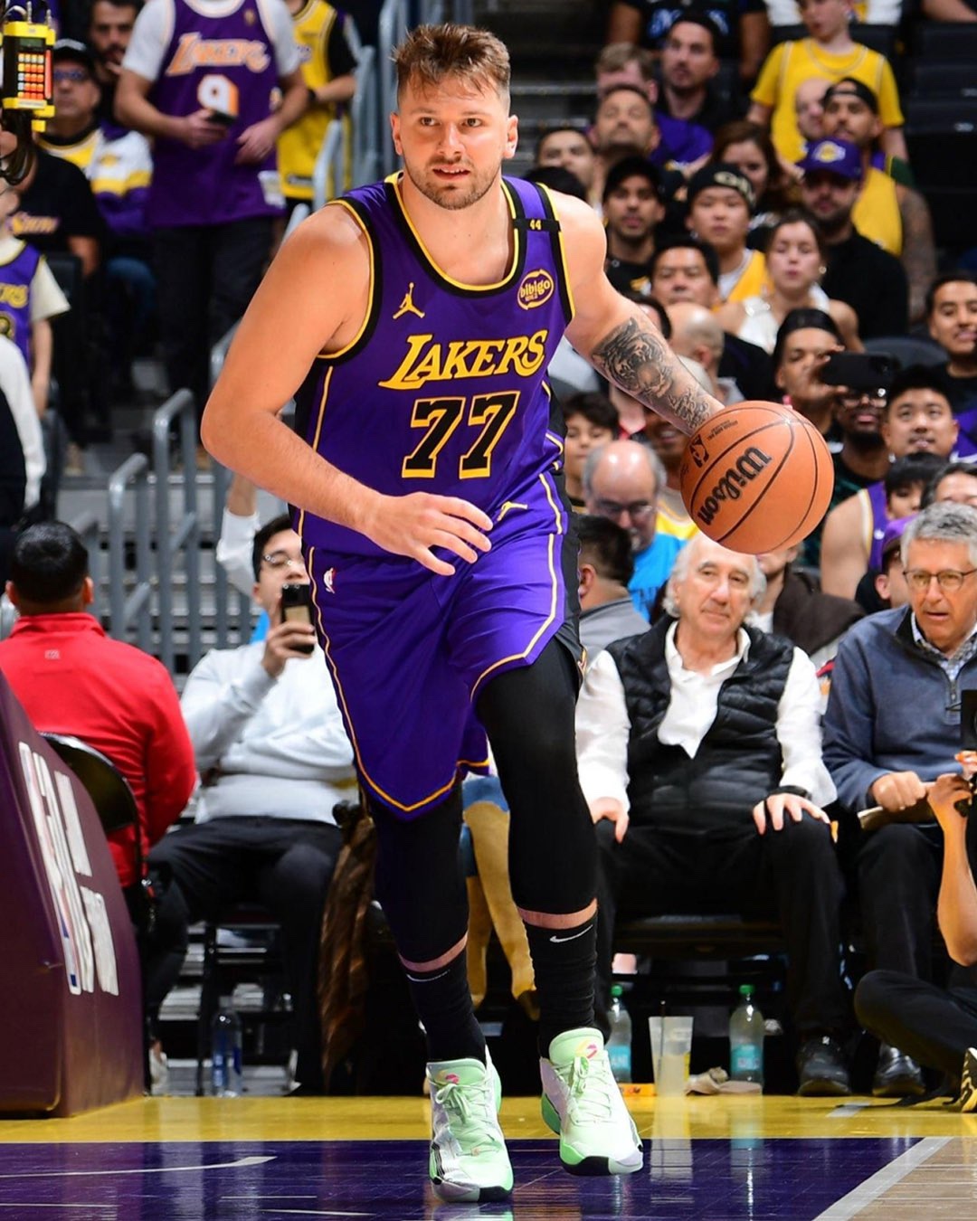 Luka Doncic wearing a custom Los Angeles Lakers jersey with number 77 while dribbling during a game. He is debuting the Jordan Luka 4 sneakers in a mint green colorway on the court