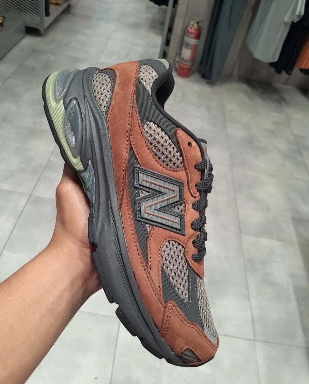 Hand holding the New Balance 2010 Brown showcasing its brown suede overlays and mesh upper