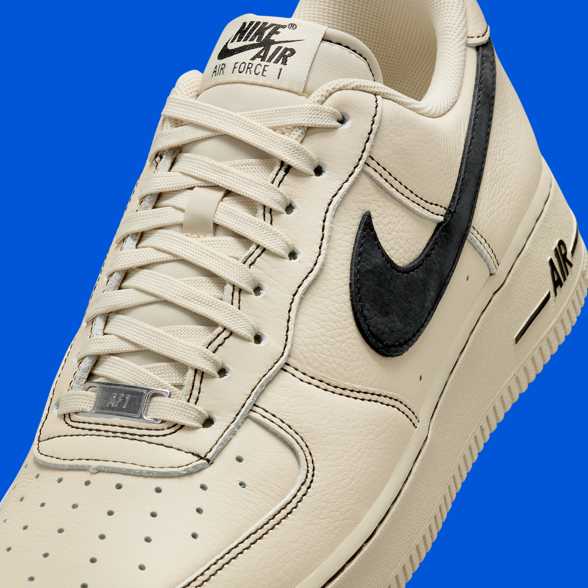 Detailed close-up of the Nike Air Force 1 Low "Light Khaki/Black" emphasizing the Black Swoosh and speckled outsole.