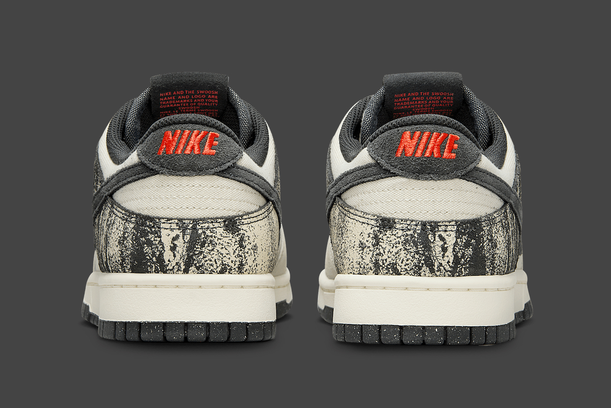 Rear view of Nike Dunk Low Pale Ivory Off Noir with red embroidered Nike heel logo.