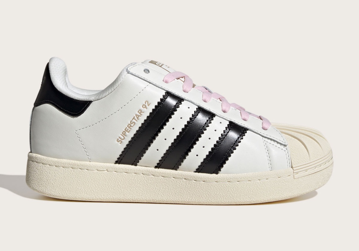 Pharrell x adidas Superstar 92 in white with black stripes and pink laces.