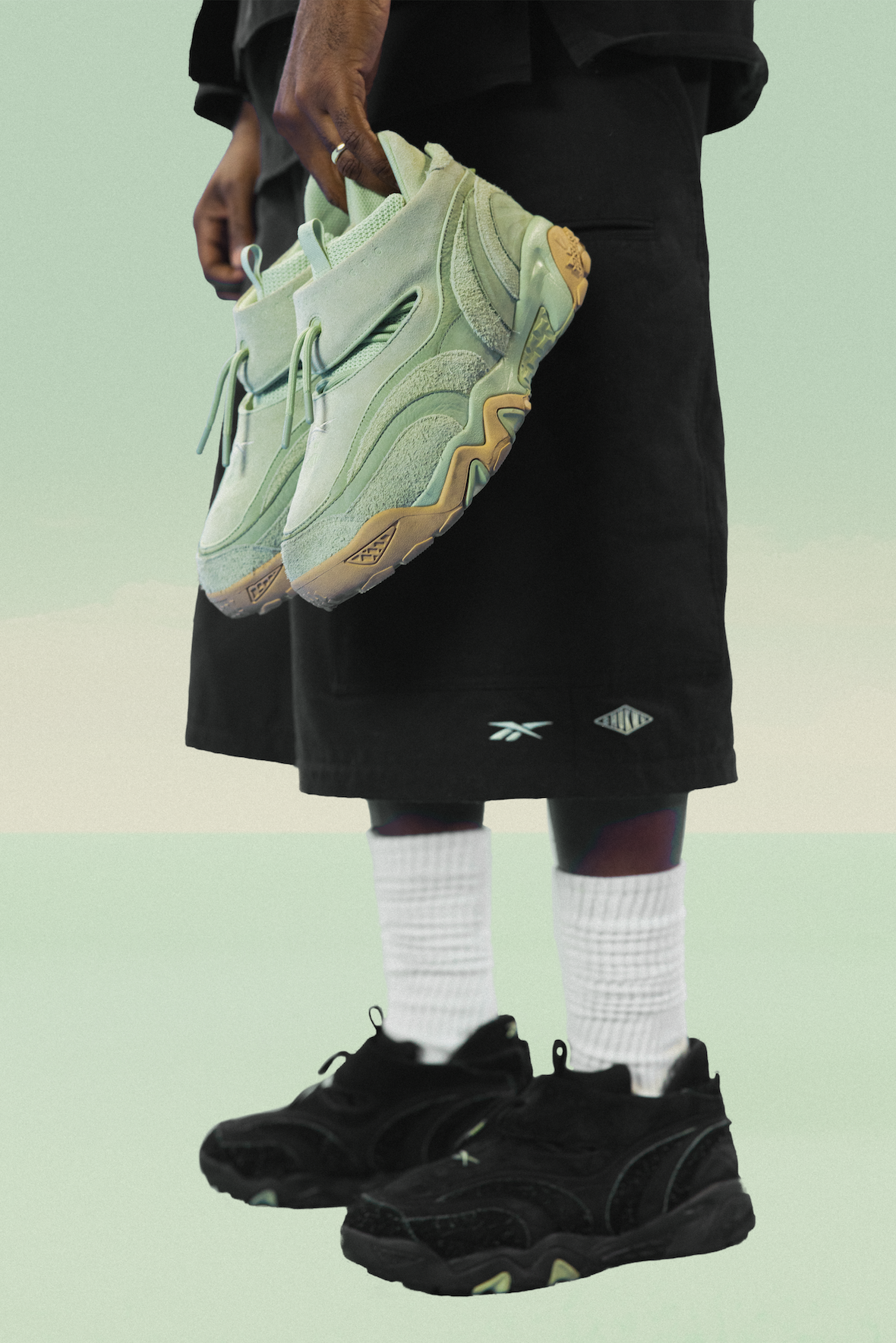 Tobe Nwigwe holding Mint Green Reebok Chukwu OTU sneakers while wearing black shorts with Reebok branding