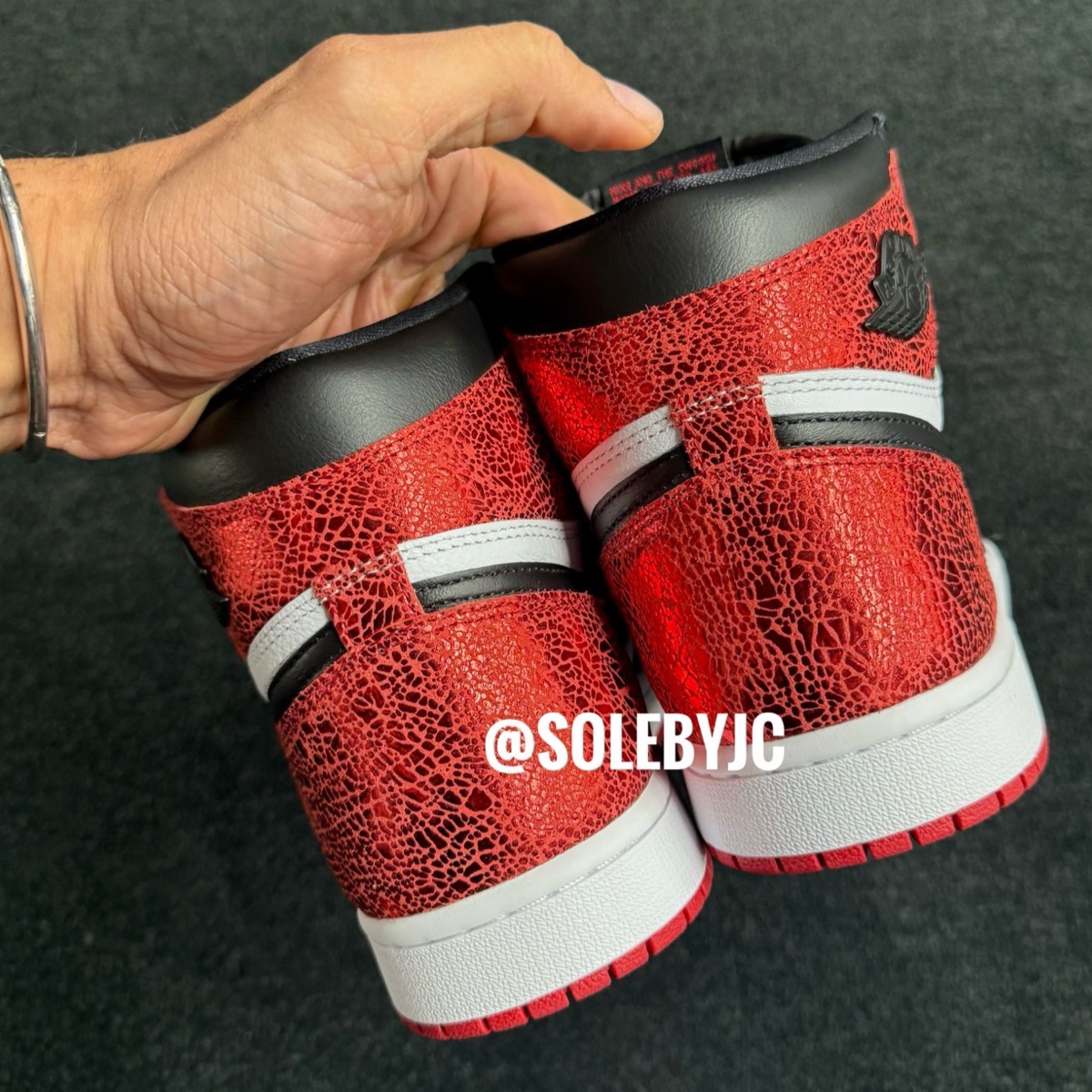 Back view of the Air Jordan 1 High OG Ruby emphasizing the distressed red leather heel design