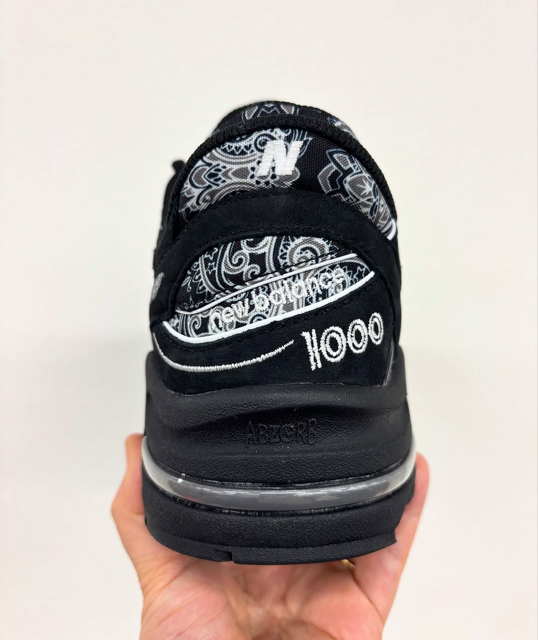 Rear view of the atmos x New Balance 1000 highlighting black suede, white embroidery, and ABZORB cushioning
