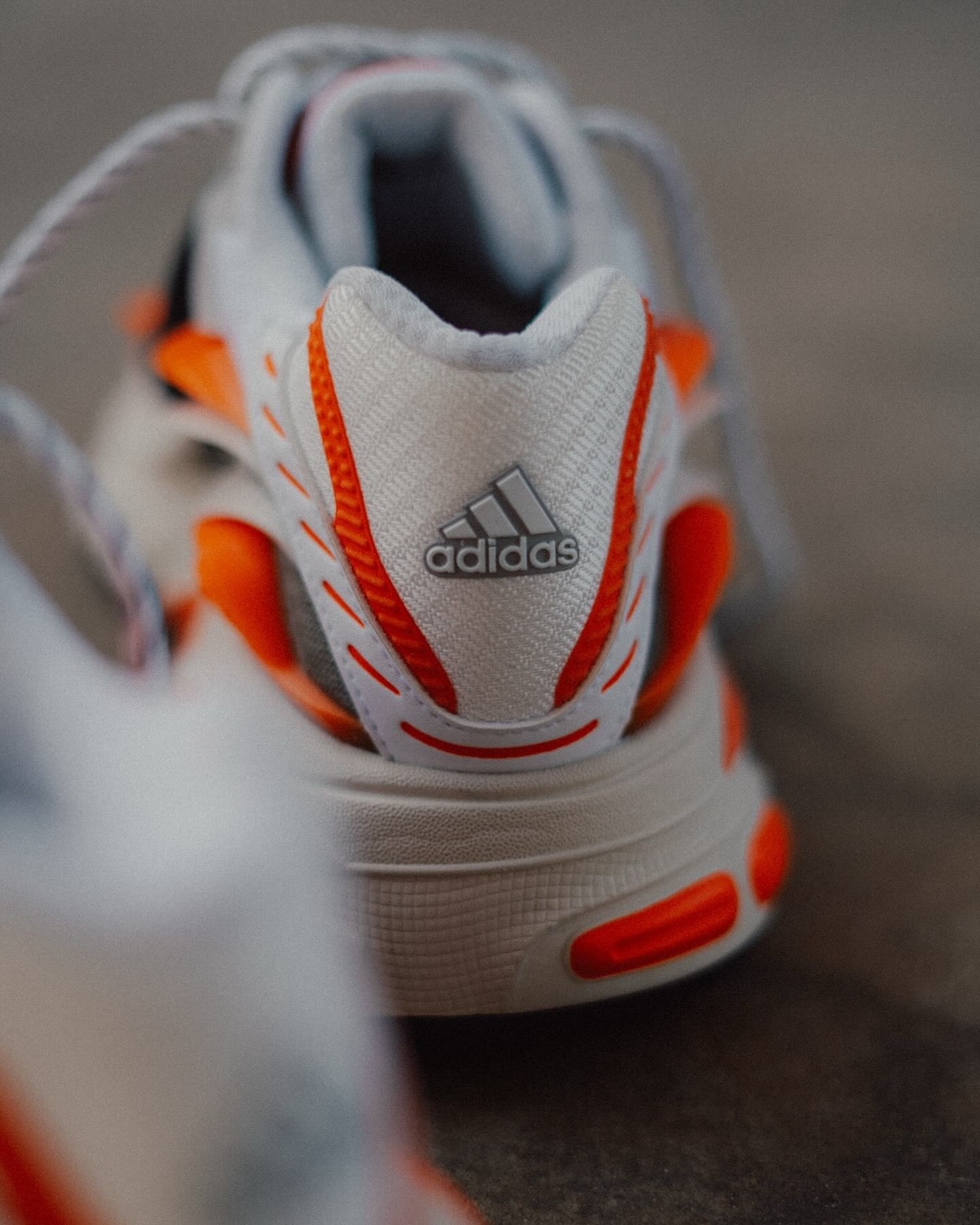 Pharrell x adidas Adistar Jellyfish Heel Branding – A rear view of the sneaker with the adidas logo on the heel, surrounded by bold orange and black details.