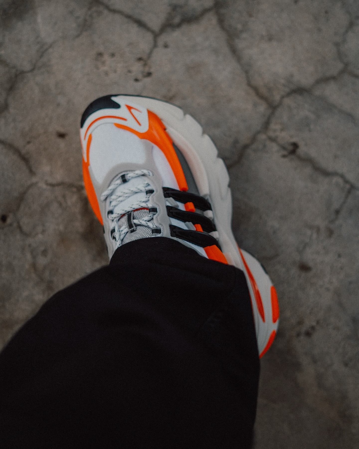 Pharrell x adidas Adistar Jellyfish Virginia Side Profile – A side view of the Pharrell x adidas Adistar Jellyfish showcasing its wavy midsole, TPU cage, and vibrant orange and black accents against a light grey mesh base.
