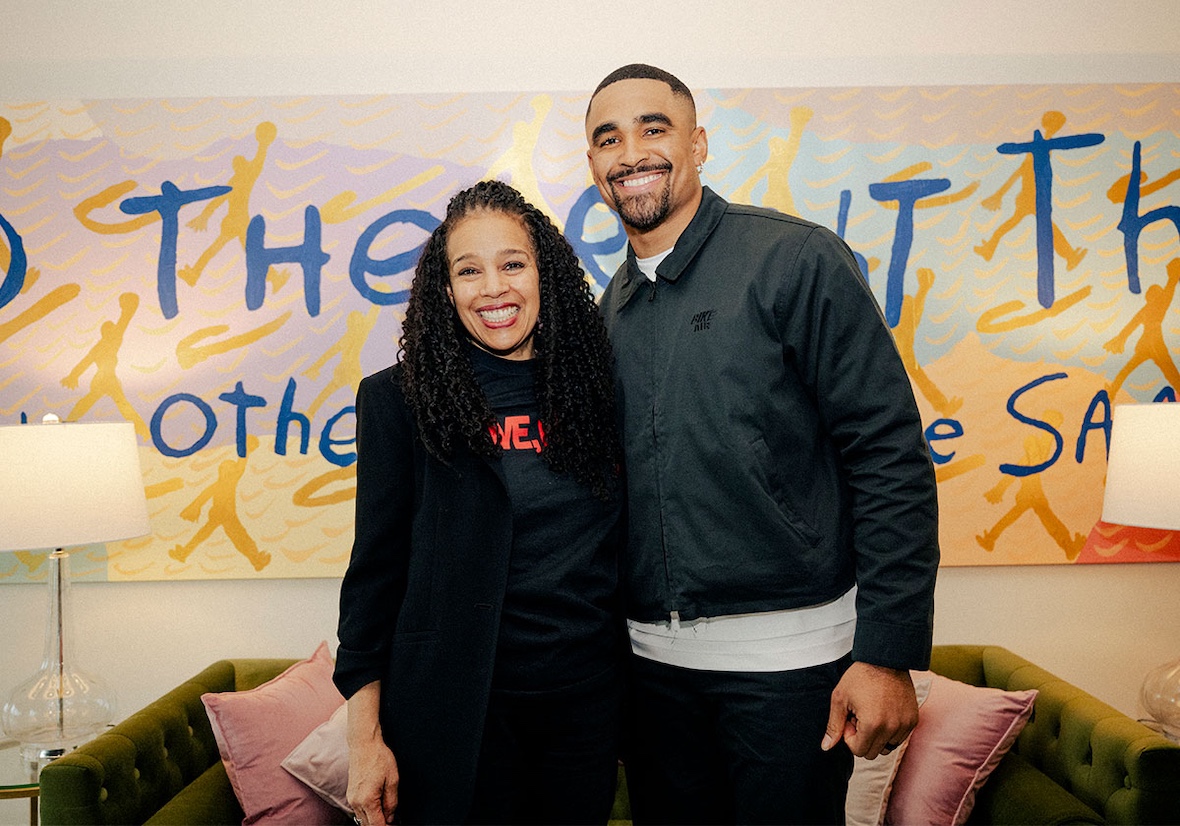 Jalen Hurts poses with Jordan Brand President Sarah Mensah in front of a motivational mural.