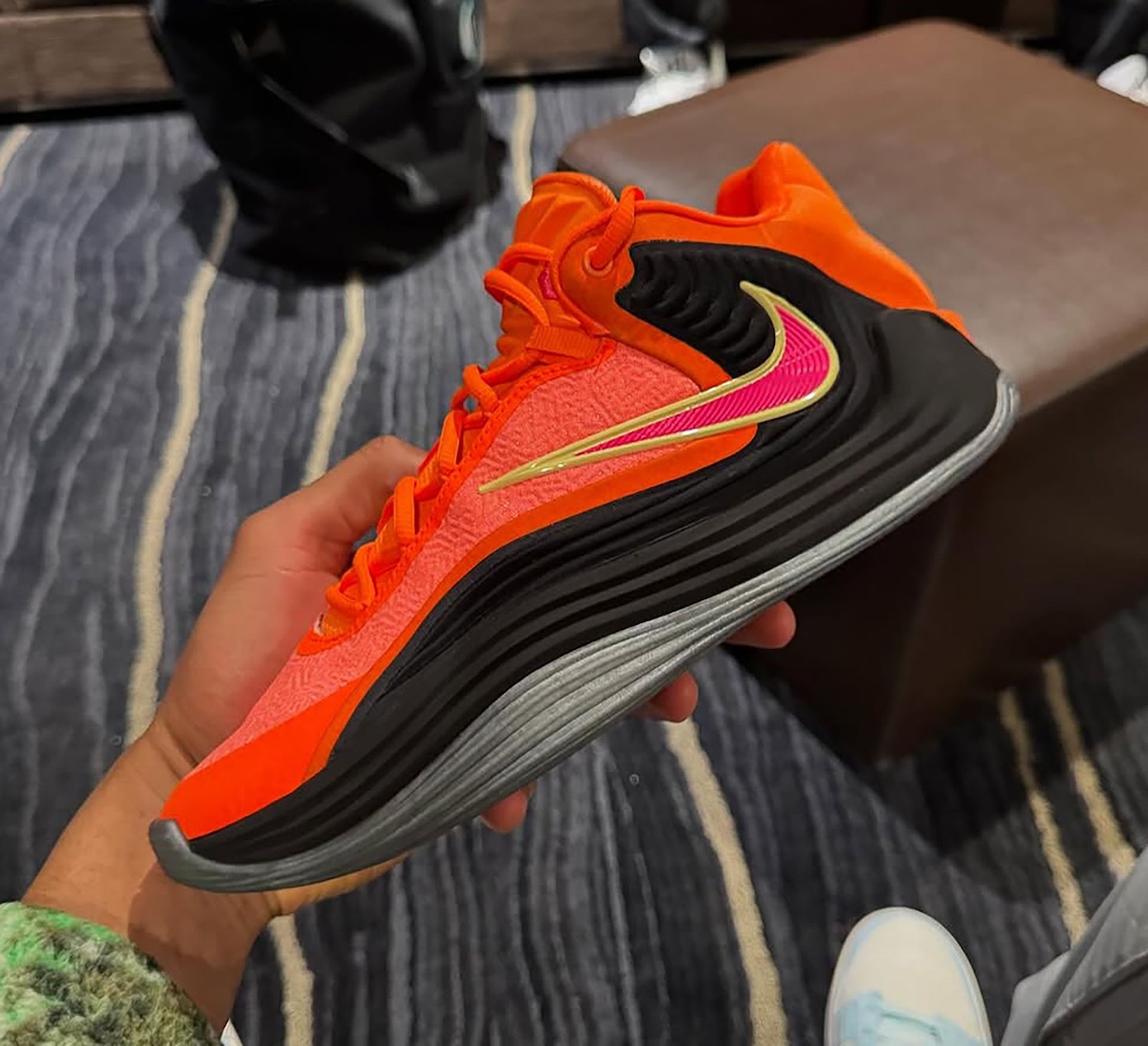 Bright orange and black Nike Zoom Freak 7 colorway held in hand
