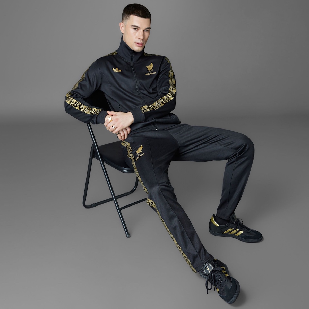 Model wearing Adidas Samba "Mexico" tracksuit and sneakers in black and gold.