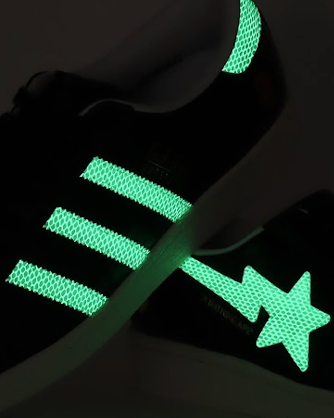 Glow-in-the-dark adidas Superstar with neon green Three Stripes and a BAPE STA logo.