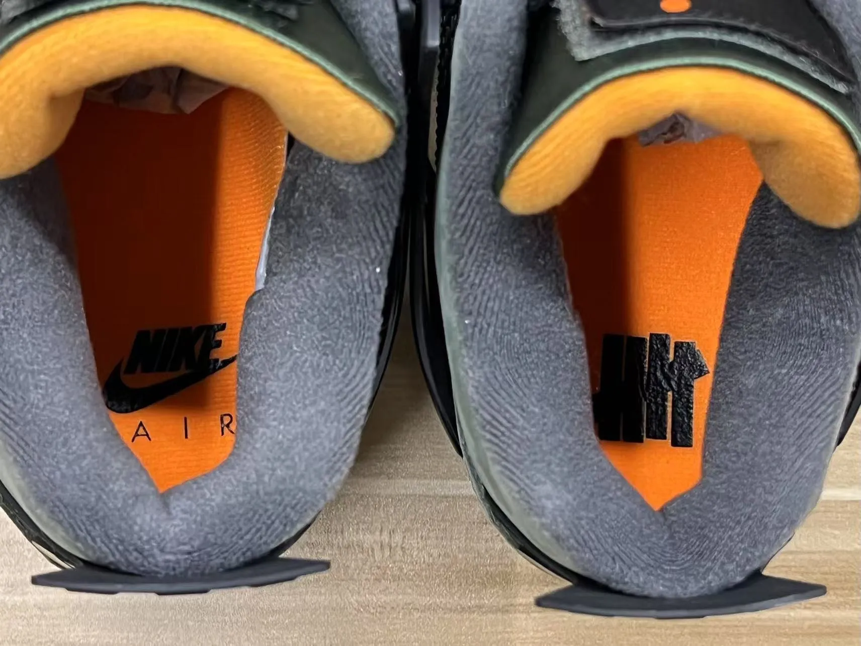 Top-down view of the Undefeated x Air Jordan 4 insoles showing Nike Air and UNDFTD logos on orange footbeds.