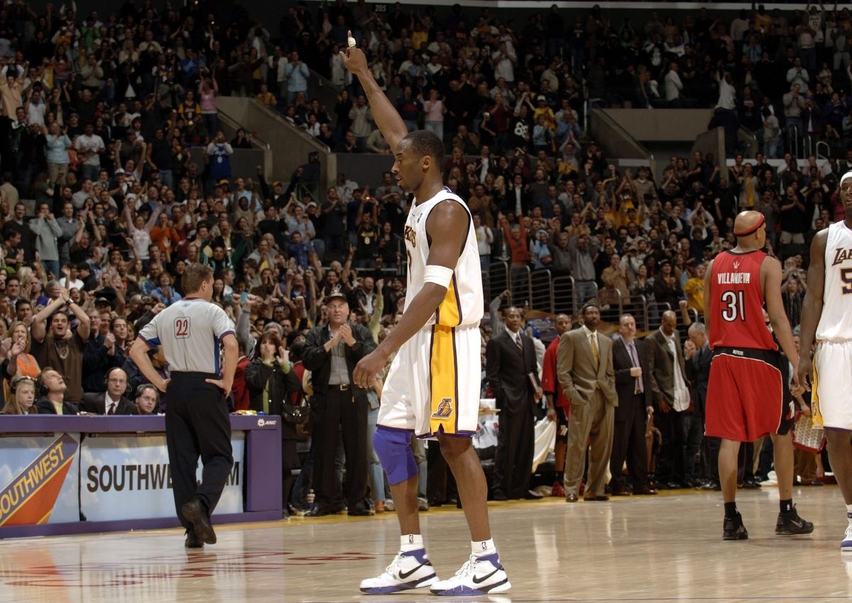 Kobe Bryant raises his arm after scoring 81 points against the Toronto Raptors in 2006, wearing a Lakers uniform and Nike Kobe 1 shoes.