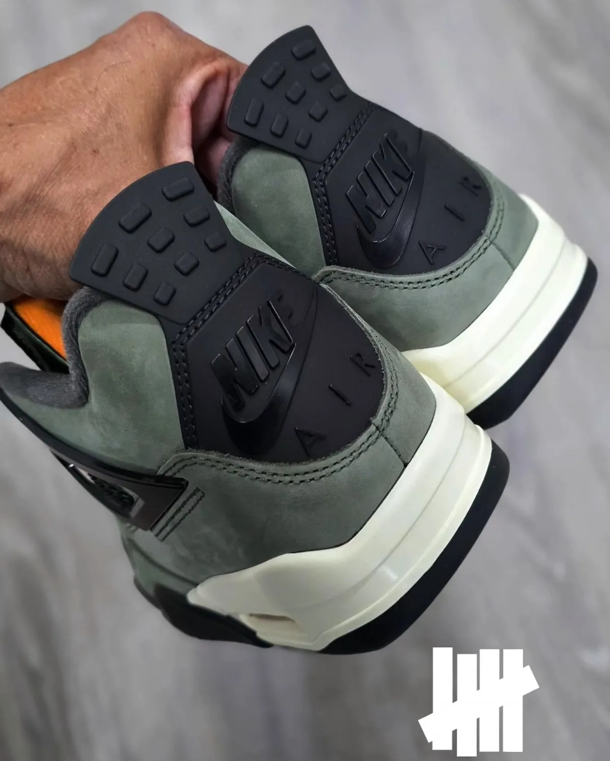 Back view of the 2025 Undefeated x Air Jordan 4 featuring Nike Air heel branding and military green suede
