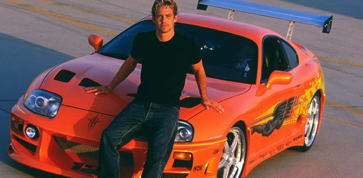 Paul Walker leaning on his Toyota Supra from Fast and the Furious