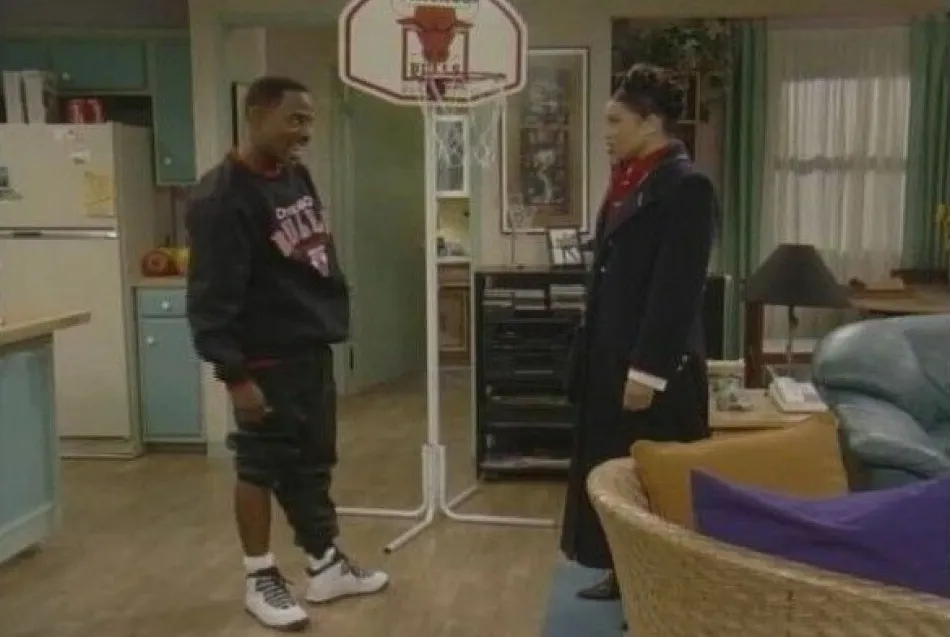 Martin Lawrence stands in his apartment on the Martin sitcom set wearing the Air Jordan 10 “Steel” next to a mini basketball hoop.